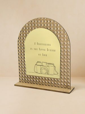 Ξύλινο επιτραπέζιο διακοσμητικό με μοτίβο rattan και καθρέπτη χρυσού χρώματος, χαραγμένη vintage κάμερα και φράση «A photograph is the pause button of life».