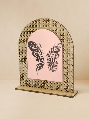 Ξύλινο επιτραπέζιο διακοσμητικό με μοτίβο rattan και καθρέπτη χρυσού χρώματος, χαραγμένη πολύχρωμη πεταλούδα και φράση ενδυνάμωσης «They whispered to her… I am the storm».