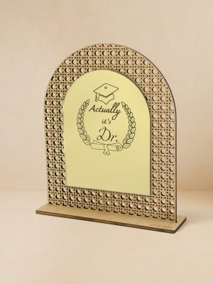 Ξύλινο επιτραπέζιο διακοσμητικό με μοτίβο rattan και καθρέπτη χρυσού χρώματος, χαραγμένα mortar board, στεφάνι δάφνης, δίπλωμα, τη φράση «Actually, it’s Dr.» και κενό χώρο για εξατομικευμένο όνομα. Ξύλινο επιτραπέζιο διακοσμητικό με μοτίβο rattan και καθρέπτη χρυσού χρώματος, χαραγμένα mortar board, στεφάνι δάφνης, δίπλωμα και φράση «Actually, it’s Dr.».