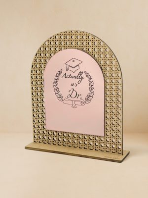 Ξύλινο επιτραπέζιο διακοσμητικό με μοτίβο rattan και καθρέπτη χρυσού χρώματος, χαραγμένα mortar board, στεφάνι δάφνης, δίπλωμα, τη φράση «Actually, it’s Dr.» και κενό χώρο για εξατομικευμένο όνομα. Ξύλινο επιτραπέζιο διακοσμητικό με μοτίβο rattan και καθρέπτη χρυσού χρώματος, χαραγμένα mortar board, στεφάνι δάφνης, δίπλωμα και φράση «Actually, it’s Dr.».