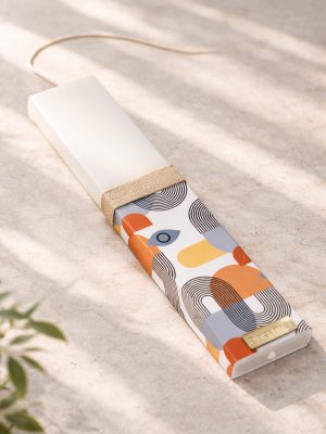 Λευκή λαμπάδα 25x4.5 με εκτύπωση Bau Grid | πορτοκαλί και γκρι γεωμετρικά σχήματα με καμπύλες γραμμές | σήμα Pnevma σε χρυσό.