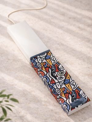 Λευκή λαμπάδα 25x4.5 με εκτύπωση Bau Grid | έντονο abstract μοτίβο σε κόκκινο μπλε και κίτρινο με γραμμές | σήμα Pnevma σε σκούρο.