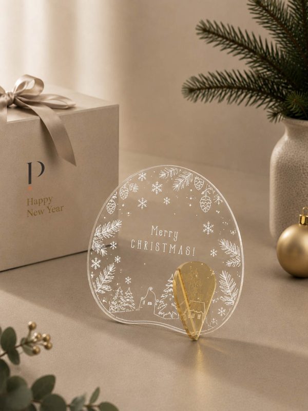 Γούρι Aurora Merry Xmas 01 με λευκές νιφάδες, μικρά έλατα και φωτεινή κυκλική εικονογράφηση.