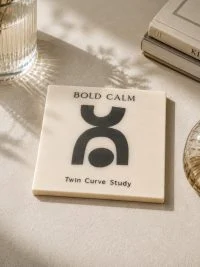 Κρεμ σουβέρ Bold Calm με μαύρες αντικριστές καμπύλες και την επιγραφή Twin Curve Study.